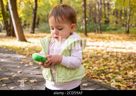 carino bambino che gioca e tiene un telefono giocattolo dentro il parco Foto Stock