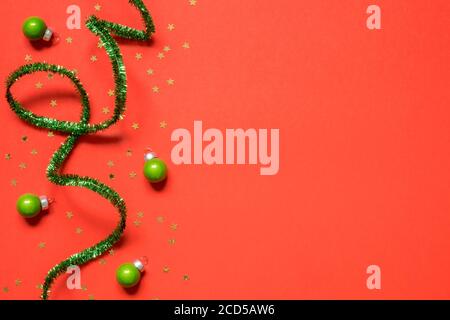 Anno nuovo o composizione di Natale 2021. Vista dall'alto sfondo in carta rossa decorativa xmas con tinsel verde e decorazioni natalizie con spazio per la copia. MOC Foto Stock