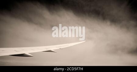 Fotografia in bianco e nero dell'ala dell'aeroplano con le nuvole dentro sfondo Foto Stock