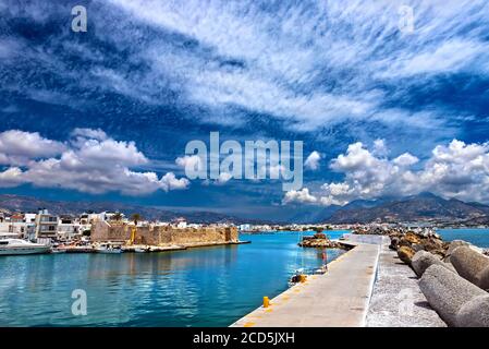Vista della città di Ierapetra 'attraverso' l'ingresso del vecchio porto, con un vecchio faro, a destra e il castello di Kales a sinistra. Creta, Grecia. Foto Stock