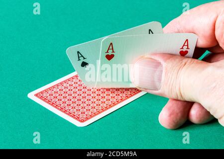 Una mano maschio che gira su un paio di assi dentro una mano di poker Foto Stock