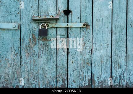 Vecchia porta in legno con tavole dipinte blu chiuse con un lucchetto. Sfondo grunge. Foto Stock