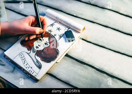 Concetto di pittura. L'artista disegna un ritratto di una donna dai capelli rossi. Bishkek, Kirghizistan - 12 marzo 2017. Foto Stock