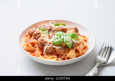 Fettuccine di pasta con polpette, parmigiano, pomodori, basilico. Foto Stock