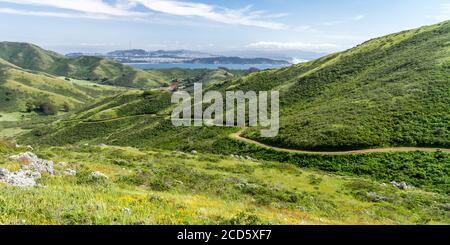 Passeggiata di primavera - il Miwok Trail conduce in una valle, con il Golden Gate e San Francisco in lontananza. Marin Headlands, California, Stati Uniti Foto Stock