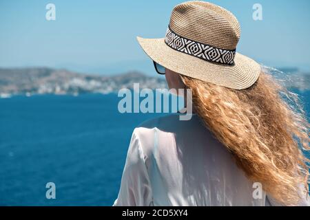 Bella giovane donna in bianco abito occhiali da sole e bikini paglia cappello con vista mare nella villa dell'hotel resort Foto Stock