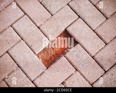 Lastre rosse per pavimentazione con un pezzo mancante. Primo piano Foto Stock