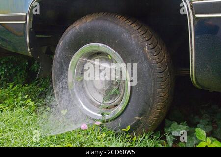 Una ragnatela di spider a imbuto che fissa uno pneumatico di un autocarro al Il terreno simboleggia il soggiorno a casa durante il coronavirus Covid-19 del 2020 pandemia Foto Stock