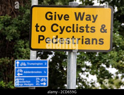 Segno di priorità ciclisti e pedoni al Roundabout.Britain primo olandese-stile rotonda aperto recentemente a Cambridge ad un costo di £2.3 milioni, dà la priorità a ciclisti e pedoni. I ciclisti hanno un anello esterno sulla rotonda, con passaggi ciclabili su ciascuna delle quattro strade di avvicinamento in una superficie rossa contrastante. Foto Stock