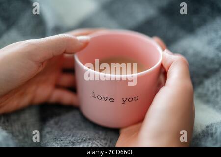 Inverno caldo caffè tazza donna rilassante a casa accogliente con coperta di lana - mattina prima colazione ragazza che beve con le parole AMORE PER CUI hai scritto su tazza rosa Foto Stock