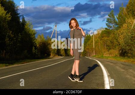 una donna in un vestito grigio sta camminando lungo il strada Foto Stock