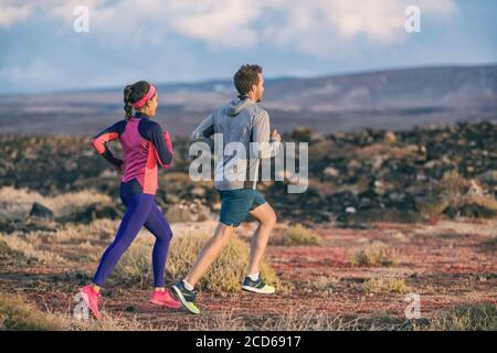 La gente che corre addestrando insieme la coppia attiva sano stile di vita che fa jogging in autunno all'aperto. Amici felici dell'uomo e della donna che si esercitano all'esterno Foto Stock