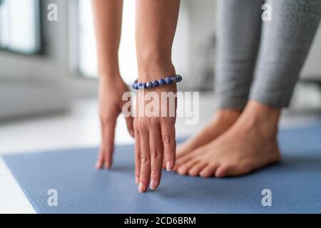 Yoga a casa esercizio in soggiorno casa - donna sul tappetino fitness che si allontana le gambe che toccano le dita dei piedi Foto Stock