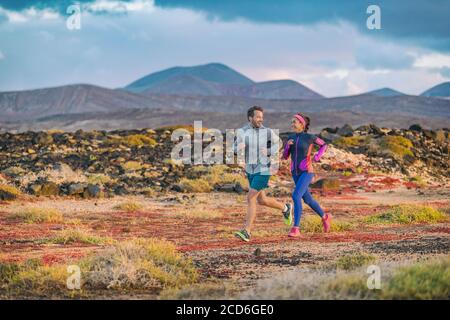 La gente che corre addestrando insieme la coppia attiva sano stile di vita che fa jogging in autunno all'aperto. Amici felici dell'uomo e della donna che si esercitano all'esterno Foto Stock