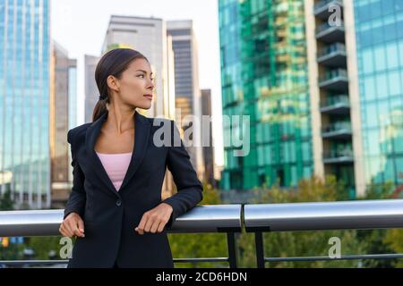 Donna d'affari asiatica ritratto di giovane donna d'affari professionale in vestito contemplativo fuori degli edifici d'ufficio. Sicuro successo Foto Stock