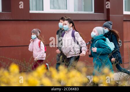 Bambini studenti in maschere mediche lasciare la scuola. Foto Stock