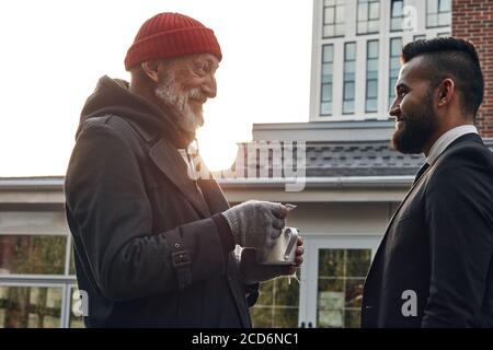 Vecchio mendicante chiedere dei soldi, uomo d'affari che cammina per strada ha risposto alla richiesta. Concetto di povertà e di questione sociale Foto Stock