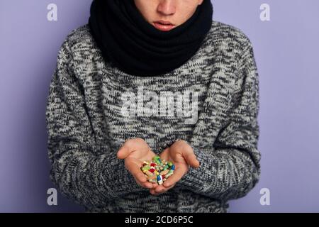 Un uomo sta tenendo un sacco di pillole colorate diverse in entrambi i suoi palme. Primo piano su foto ritagliata Foto Stock