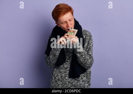 giovane uomo che va a masticare, morso, pillole gran. primo piano ritratto, isolato sfondo blu Foto Stock