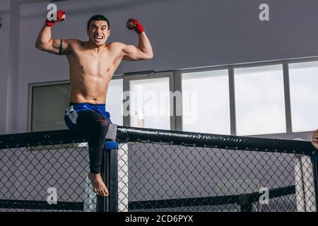 Il campione Heavyweight Light overjoyed in posa dopo la partita di boxe celebra un vittoria in campionato seduto in posa vincitore su corrimano ad anello Foto Stock