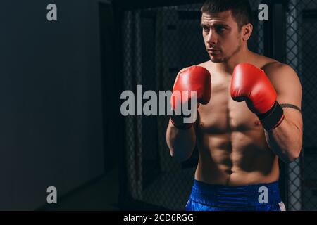 Addestramento del pugile maschile atletico allo studio di boxe. Ritratto di un uomo caucasico dai capelli scuri in difesa. Concetto di persone e boxe Foto Stock