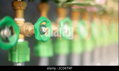 Fila di tubazioni industriali e valvole con ruote verdi su parete grigia per controllare il livello dell'acqua standard in il dormitorio per controllare il prezzo Foto Stock