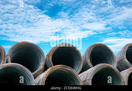 Bobina di filo di acciaio contro cielo blu. Acciaio metallico rinforzato per la costruzione di calcestruzzo. Filo di ferro per l'industria edile. Bobina o rotolo di acciaio argentato Foto Stock