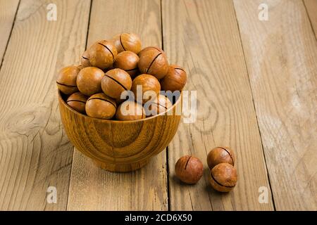 Noci di macadamia naturale organica in ciotola su tavola di legno piatto Vista dall'alto i noci di snack sani contengono l'olio essenziale ricco di vitamine B e PP, molto Foto Stock