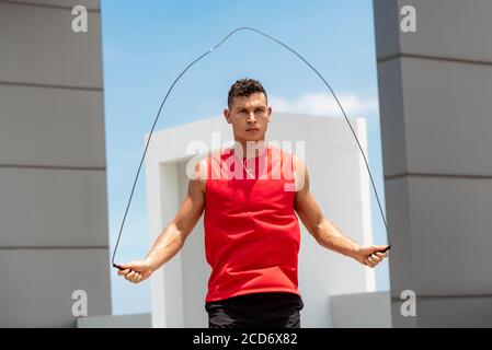 Bell'atleta caucasico facendo la mattina all'aperto esercizio di salto corda sopra edificio sul tetto Foto Stock