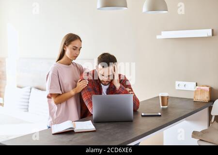 Charming gentile femmina vuole sostenere sconvolto, tristemente guardando uomo, mette mano sulla spalla teneramente, guarda via, tristezza espressiva, concetto di sostegno familiare Foto Stock