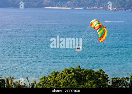 Parapendio sopra gli alberi e il mare, Patong, Phuket, Thailandia Foto Stock