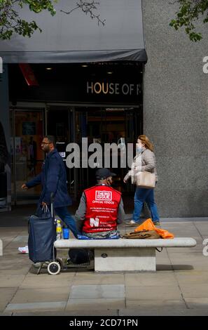 Londra, Inghilterra, Regno Unito. Venditore di grande edizione seduto fuori Casa di Fraser in Oxford Street Foto Stock