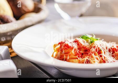 Pasta con tomatos in un piatto servito su un legno tabella Foto Stock