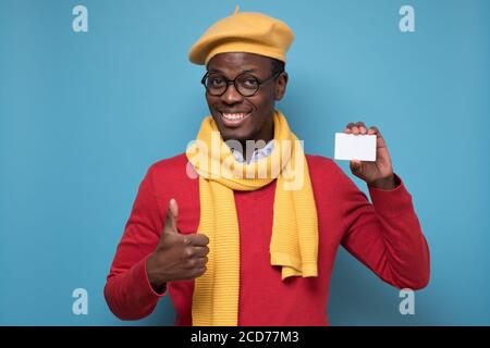 Uomo afro-americano che tiene una carta vuota mostrando il pollice in su. Foto Stock