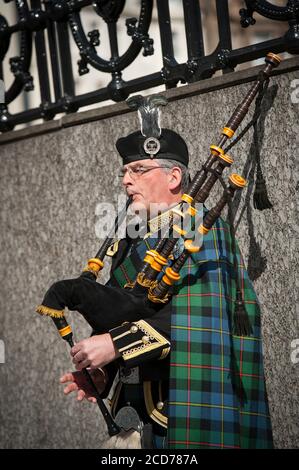 Suonatore di cornamusa vestito con tartan scozzese tradizionale che suona le cornamuse su una strada a Edimburgo, Scozia. Foto Stock