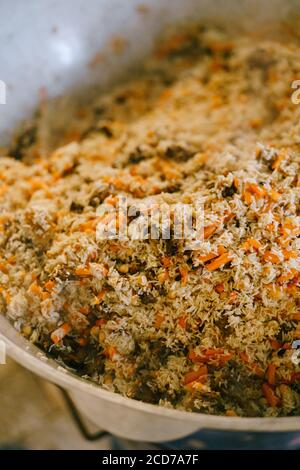 Primo piano del pilaf uzbeko finito in azan. La consistenza del riso, della carne e delle carote. Foto Stock
