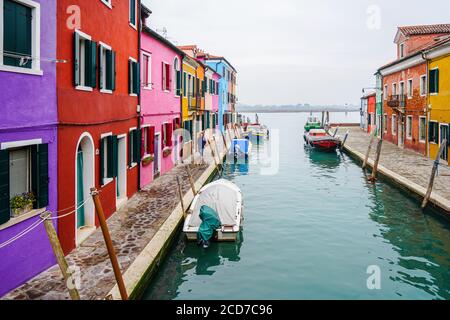 Venezia, Italia - Gennaio 2020: Case colorate sull'Isola di Burano lungo il pittoresco canale con barche ormeggiate sul fiume Foto Stock