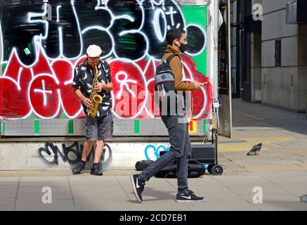 Londra, Inghilterra, Regno Unito. Busker suonava il sassofono davanti ai graffiti di Oxford Street Foto Stock