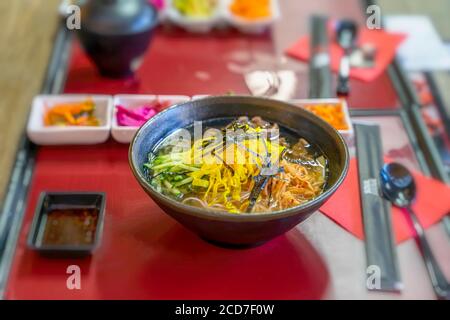 Zuppa in stile asiatico con tagliatelle di udon, fette di manzo, primi piani di verdure in una ciotola sul tavolo, vista dall'alto. Foto Stock