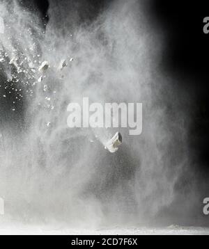 nube di farina bianca di grano su sfondo nero, particelle volare in direzioni diverse, esplosione e schizzi Foto Stock