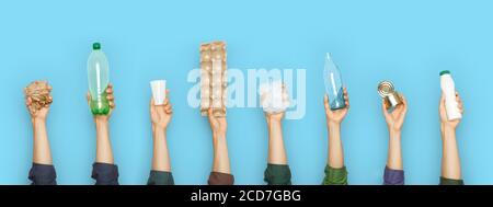 Mani che tengono diversi rifiuti , plastica, metallo, vetro e carta su sfondo blu. Foto Stock