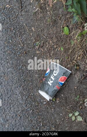 Tazza di bevande da asporto KFC (creduto essere carta) sul lato di una strada di campagna. Concetto di lettiera da asporto, spazzatura del fast food. Foto Stock