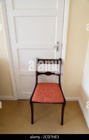 Sedia da pranzo che tiene una porta chiusa in una camera da letto in una casa suburbana, Londra, Inghilterra, Regno Unito Foto Stock