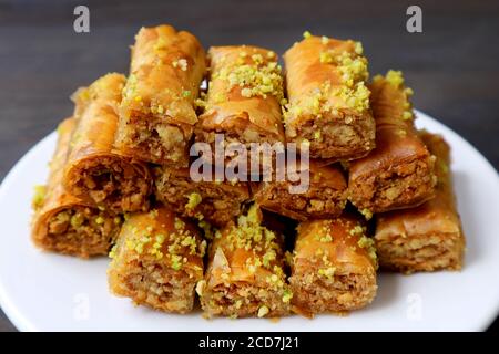 Piatto di deliziosi pasticcini Baklava con noci pistacchio tritate Su tavolo nero Foto Stock