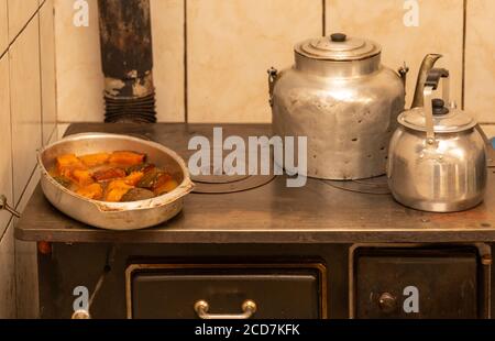 Vista su una stufa a legna con due bollitori e un vassoio in metallo riempito di zucca zuccherata e caramellata. Preparazione del pranzo giornaliero. Cucina brasiliana Foto Stock