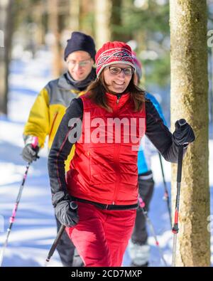 Un gruppo di buon umore la gente facendo escursioni con le racchette da neve tour nella natura invernale in una fredda giornata soleggiata Foto Stock