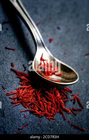 Lo zafferano in un cucchiaio su uno sfondo scuro, il fuoco selettivo, macro shot, profondità di campo Foto Stock