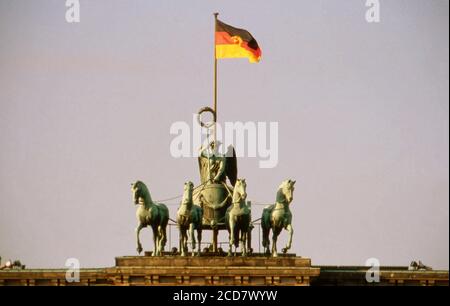 Bildreportage: Berlin kurz nach dem fall der Mauer, hier der Blick auf die Quadriga auf dem Brandenburger Tor über der noch die Flagge der DDR weht, Deutschland, Dezember 1989. Foto Stock