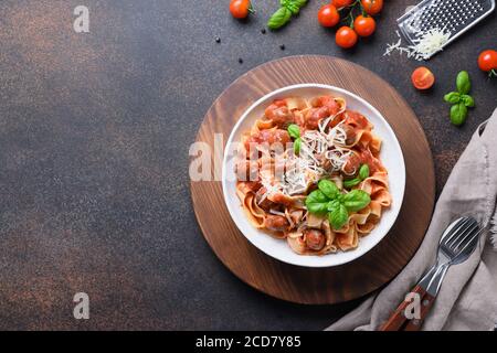 Fettuccine di pasta fatta in casa con polpette, parmigiano, pomodori, basilico sul marrone. Foto Stock