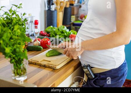 Donna incinta con pompa insulinica che prepara cibo sano nel cucina Foto Stock